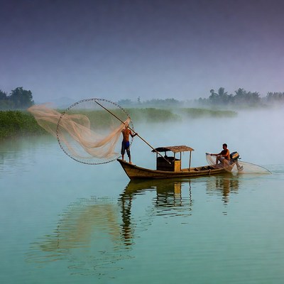 Asian fishermen casting net from boat