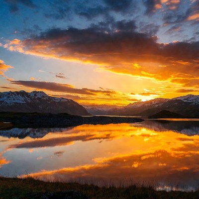 Sunset over snowy mountains and lake