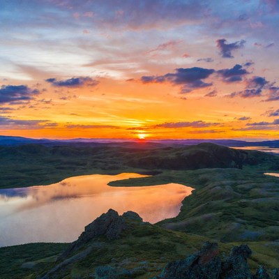 Sunset over green hills and lake