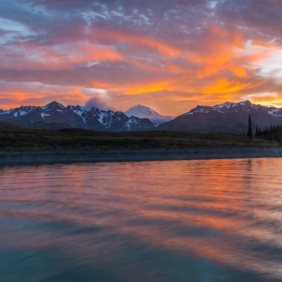Sunset over snowy mountains reflecting in lake