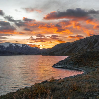 Sunset over snowy mountains and lake