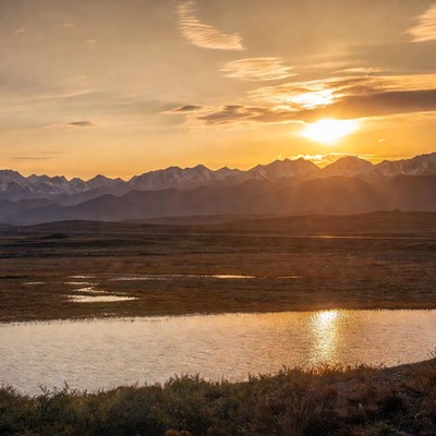 Sunset over snowy mountains and lake