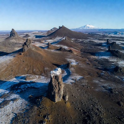 Snowy Volcanic Landscape with Distant Snowcapped Mountain