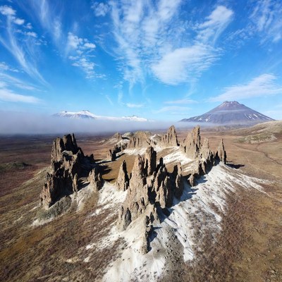 Snowy Rock Formations with Distant Volcano