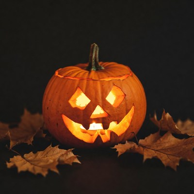 Lit Jack-o'-lantern on Autumn Leaves