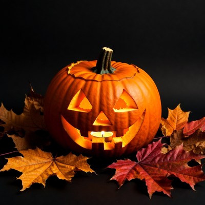 Lit Jack-o-Lantern with Autumn Leaves