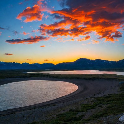 Sunset over curved lake and mountains