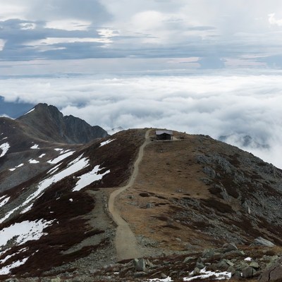 Mountain hut on snowy trail above clouds