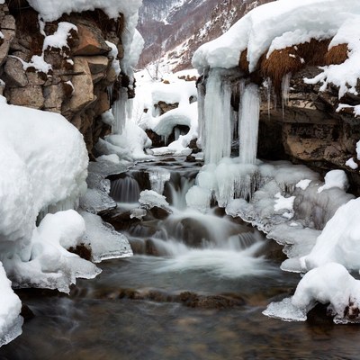 Icy Stream Flowing Between Snowy Rocks