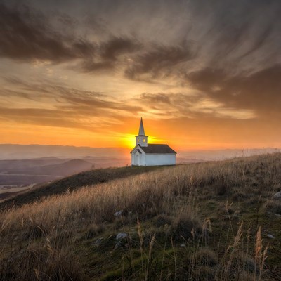 White chapel on hill at sunset