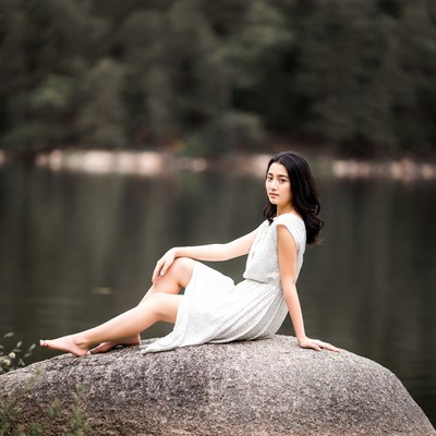Asian woman sitting on rock by lake