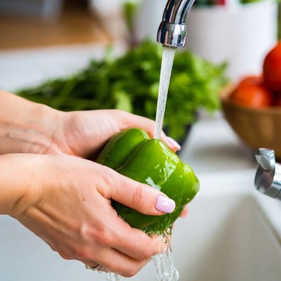 Woman washing green bell pepper
