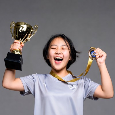 Asian girl holding trophy and medal