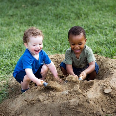 Two boys digging in sand pile