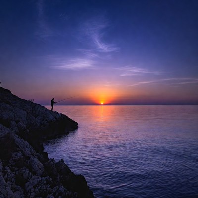 Man fishing at sunset from rocky cliff