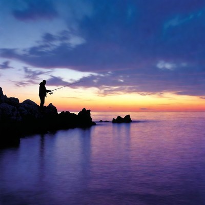 Silhouette man fishing at sunset