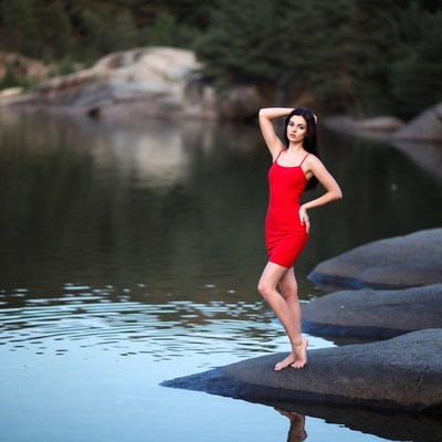 Woman in red dress on lakeside rocks
