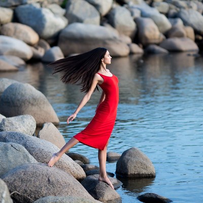 Asian woman dancing on riverside rocks