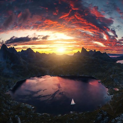 Sailboat on lake amid sunset mountains