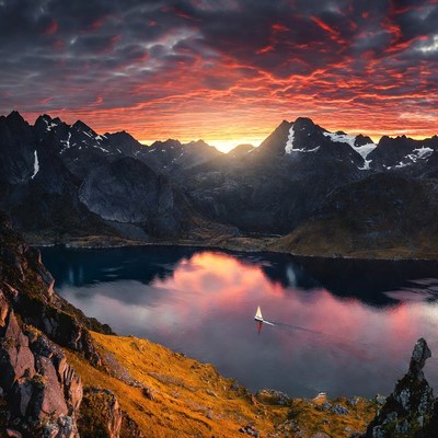 Sailboat on lake amid sunset mountains