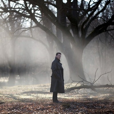 Man in trench coat in foggy forest