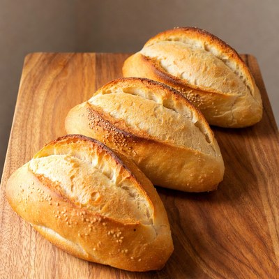 Three Fresh Baguette Rolls on Wooden Board
