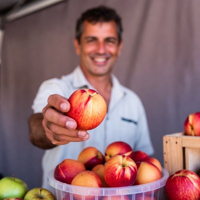 Smiling man holding peach at market