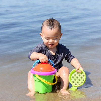 Asian baby playing with bucket at beach