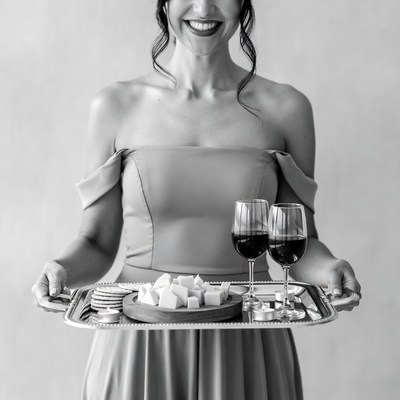 Woman holding cheese tray and wine glasses