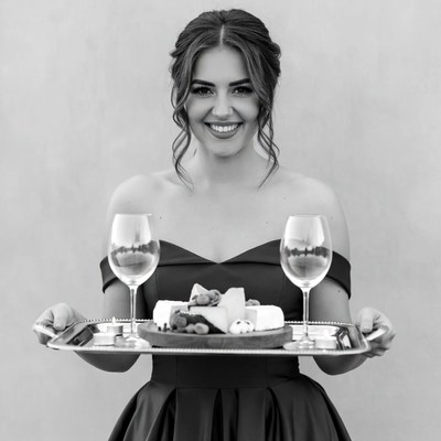 Woman holding cheese platter with wine glasses