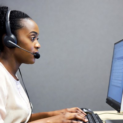 African-American woman working at computer with headset