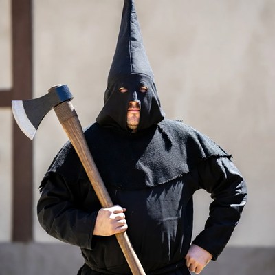 Man in black pointed hood holding axe
