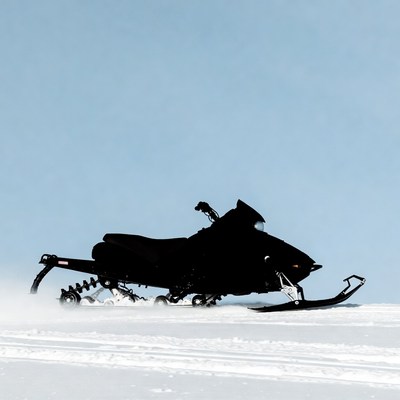 Black snowmobile silhouette on snowy trail