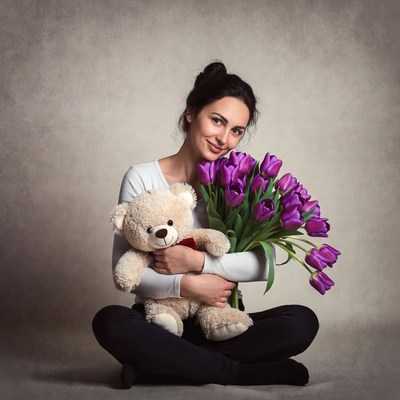 Woman holding teddy bear and tulips
