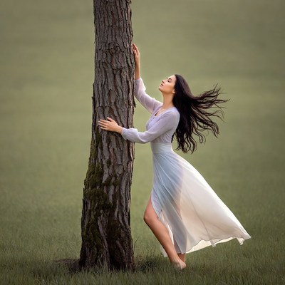 Woman embracing tall tree in grass