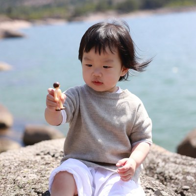 Asian toddler holding toy figure seaside