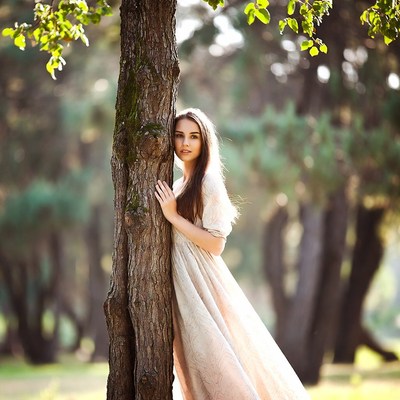 Woman peeking from tree in forest