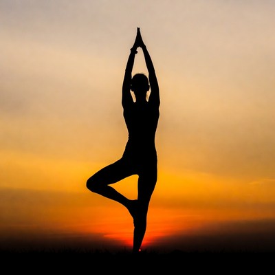 Woman in tree pose yoga silhouette sunset
