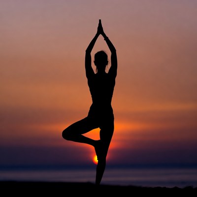 Woman in tree pose yoga silhouette sunset