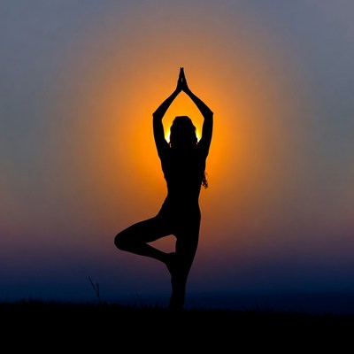 Woman in tree pose silhouette at sunset