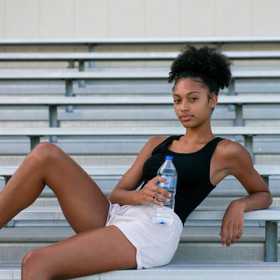 African-American woman holding water bottle on bleachers