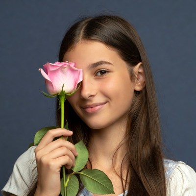 Girl holding pink rose over eye