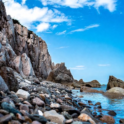 Rocky Sea Cliff with Pebbles and Blue Water