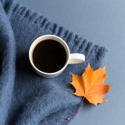 Black Coffee Cup with Autumn Leaf on Blue Blanket