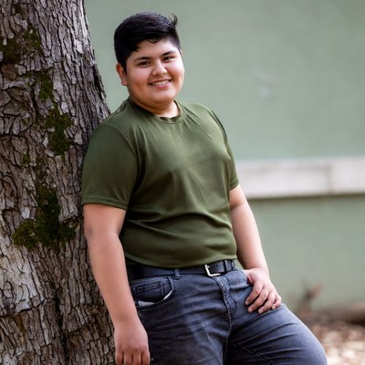 Smiling Latino boy leaning on tree
