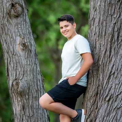 Teen boy leaning against tree