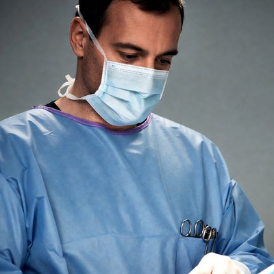Surgeon wearing mask holding forceps