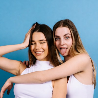 Two women sticking tongue out hugging
