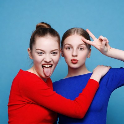 Two girls sticking tongue out peace sign