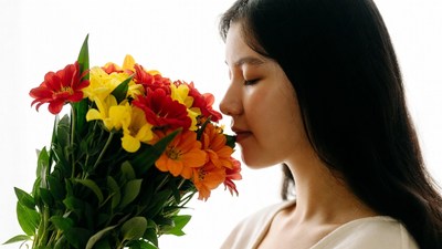 Asian woman smelling colorful flowers